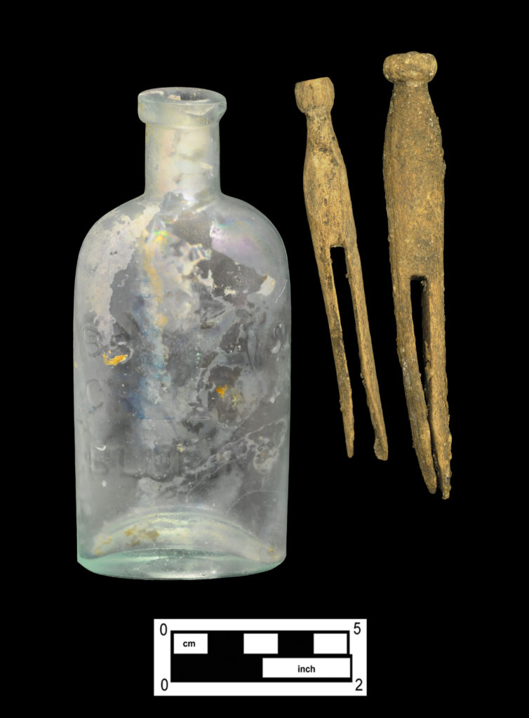 Laundry-related artifacts: aqua bottle embossed “Sawyer’s Crystal Blueing” (4A-G-0149) and two wooden clothes pins (Cat # 4.24.564).