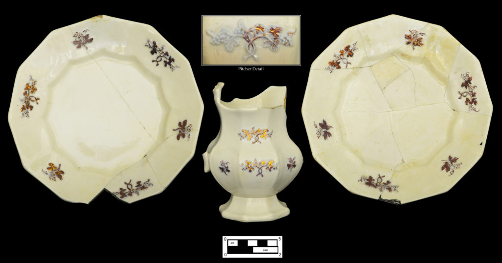 Partial set of bone china decorated with blue grape sprig and purple luster highlights: pair of 12-sided paneled plates (4A-C-0013; 4A-C-0103) with matching creamer (4A-C-0104).